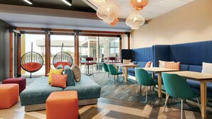 A modern lounge area with seating, tables, and hanging chairs. - Tru by Hilton Williamsville Buffalo Airport (Buffalo)