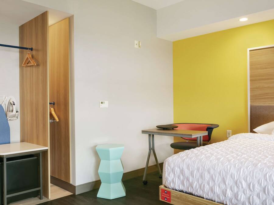 Ett hotellrum med en säng, ett skrivbord, en stol, ett litet bord och en garderob.