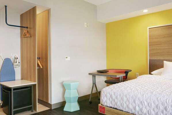 Una habitación de hotel con cama, escritorio, silla, mesita y armario.