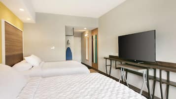Habitación de hotel con dos camas, televisión y escritorio.