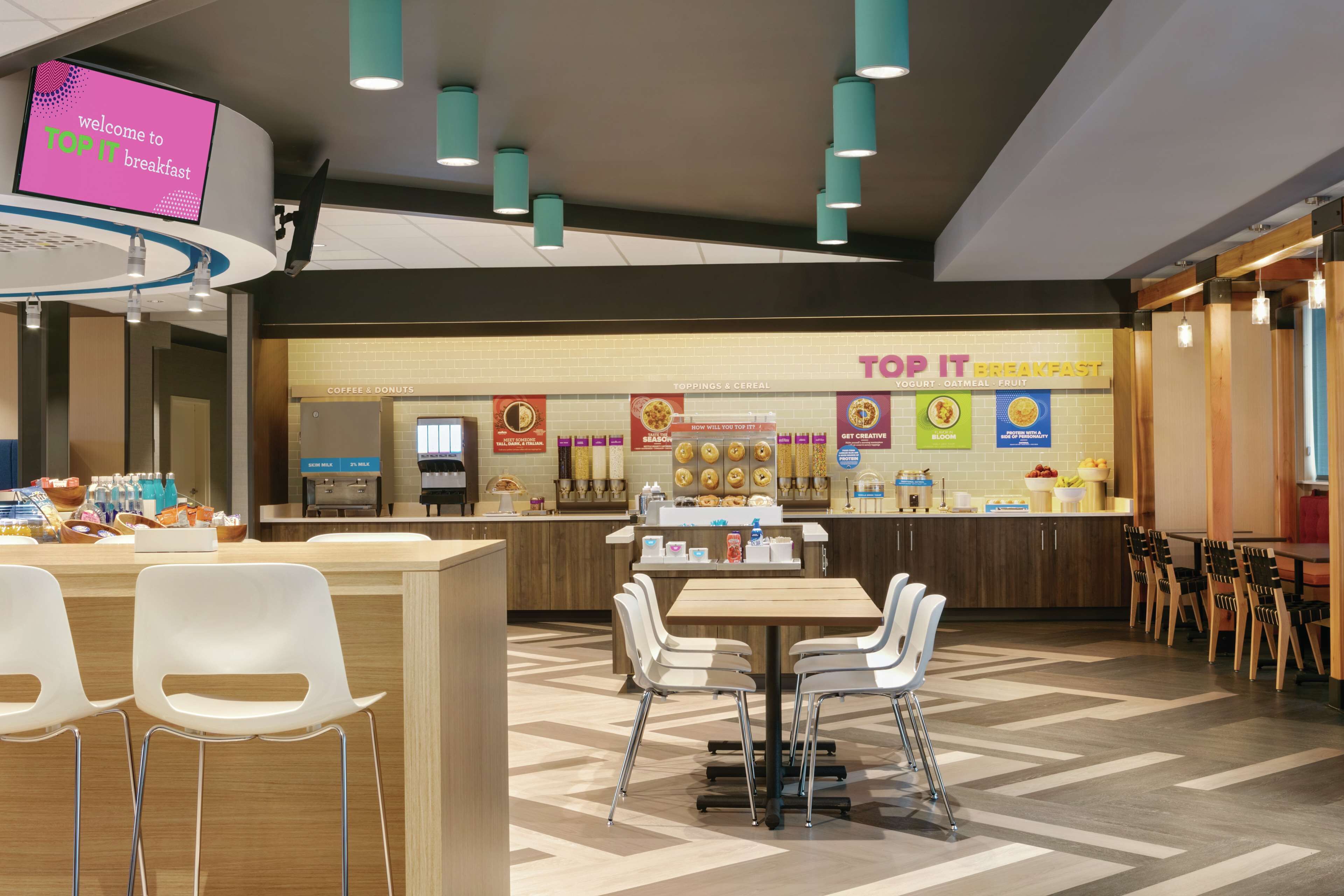 A Top It breakfast area with a counter, seating, and a digital sign.