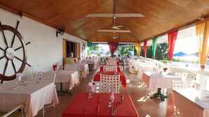 Ein Restaurant mit mehreren Tischen, weißen Stühlen und einer großen Schiffslenken-Dekoration an der Wand.