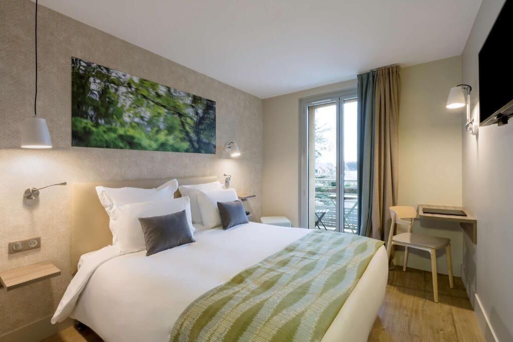 Una habitación de hotel moderna con una cama grande, un escritorio y un balcón con vistas.