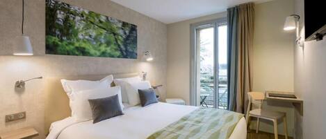 A modern hotel room with a large bed, a desk, and a balcony with a view.