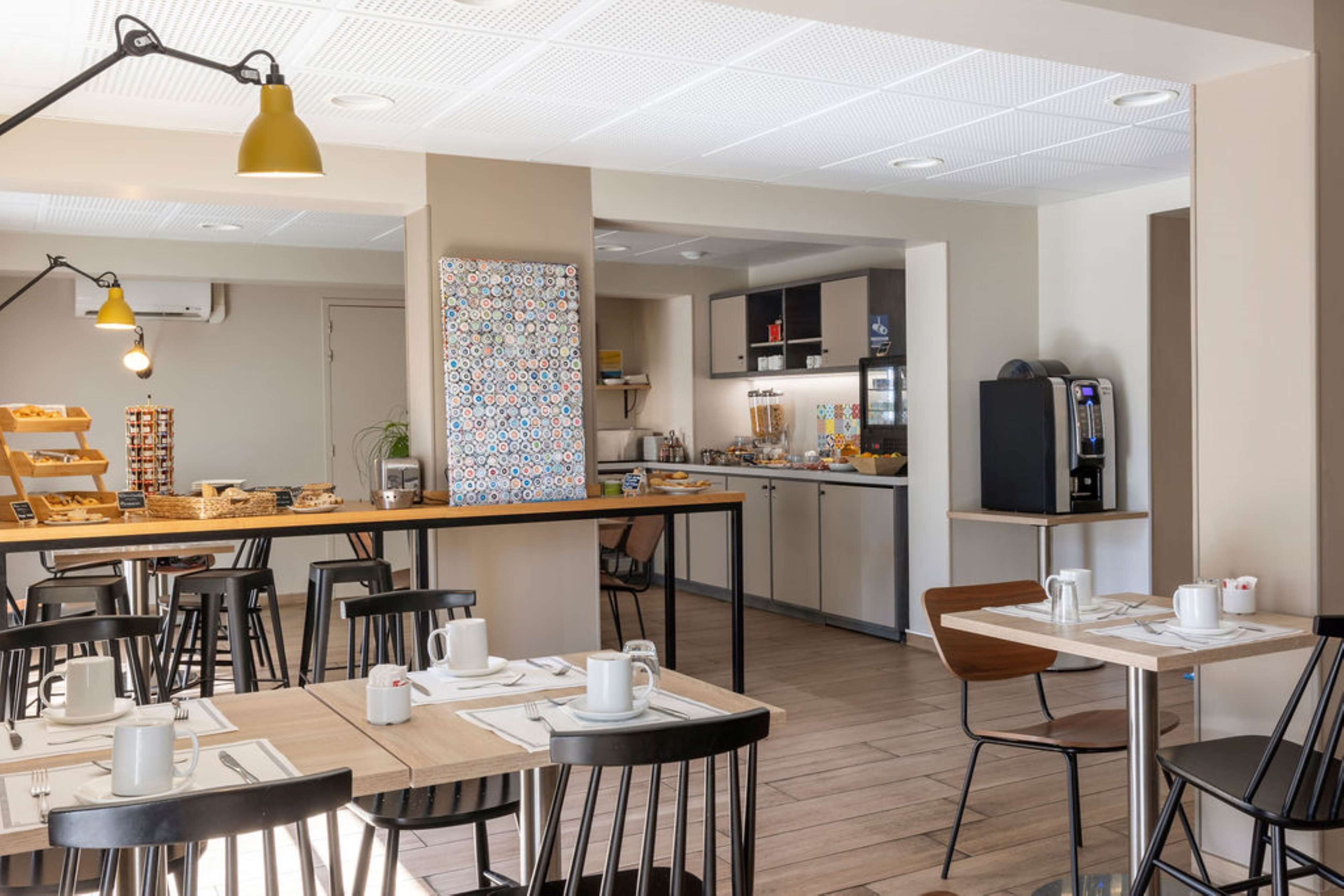 Un café moderne doté de plusieurs espaces de détente, d’une machine à café et d’un assortiment de produits pour le petit-déjeuner présentés sur le comptoir.