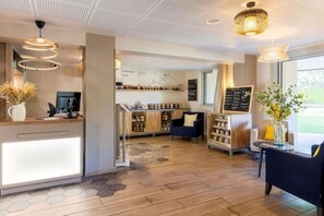 Een modern interieur met een receptiebalie, houten vloeren en een zithoek met uitzicht op het buitenland.