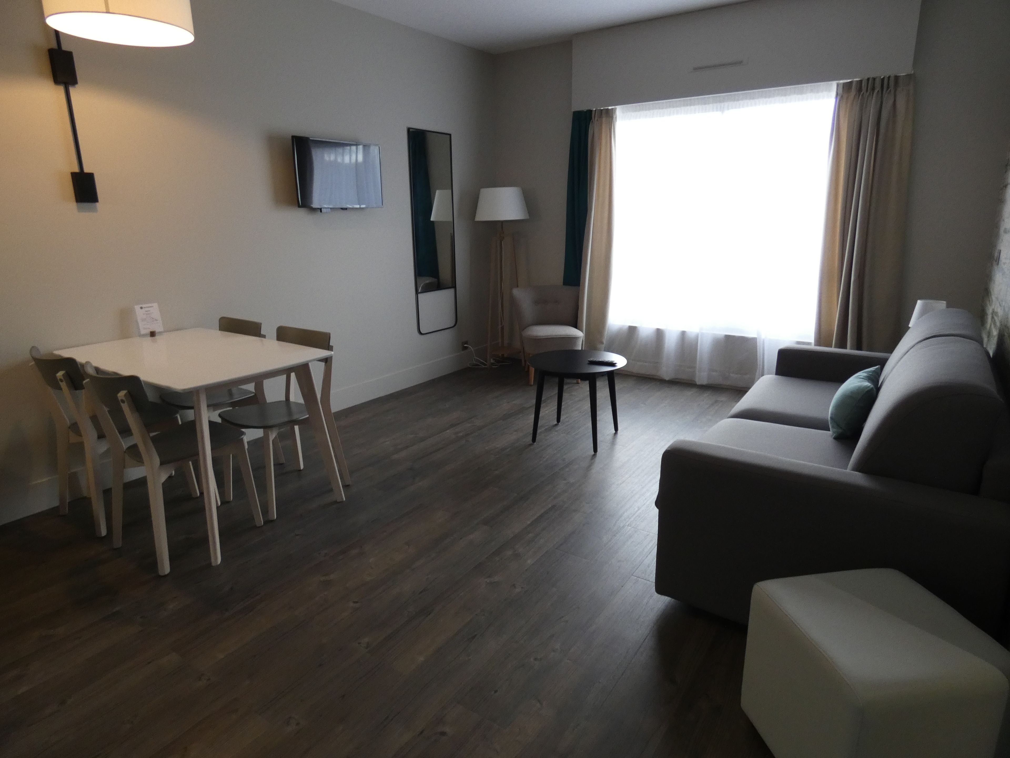 Una sala moderna con una mesa de comedor, sofá y televisor montado en la pared.