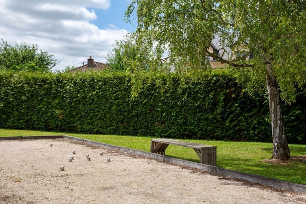 A croquet field with a wooden bench and a hedge in the background.