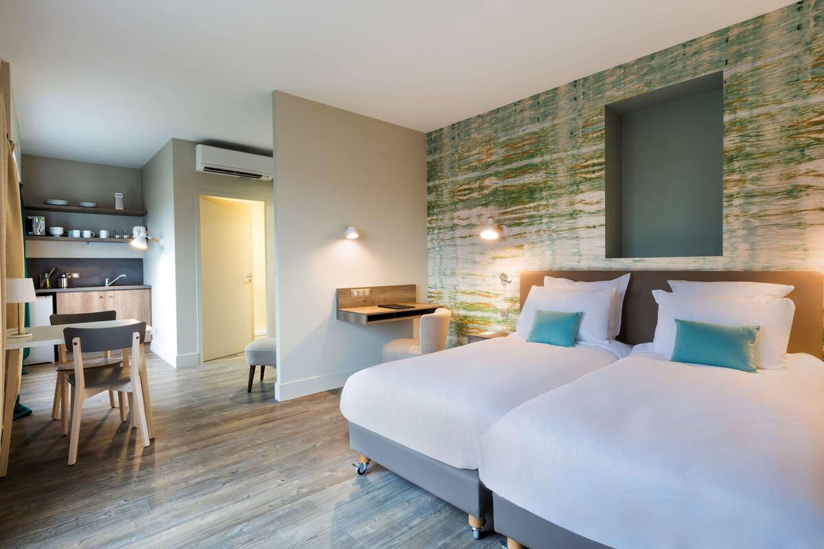 Une chambre d’hôtel moderne équipée d’un grand lit, d’un bureau et d’une kitchenette.