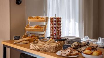 Un bufé de desayuno con diversos pasteles, pan y mermeladas.
