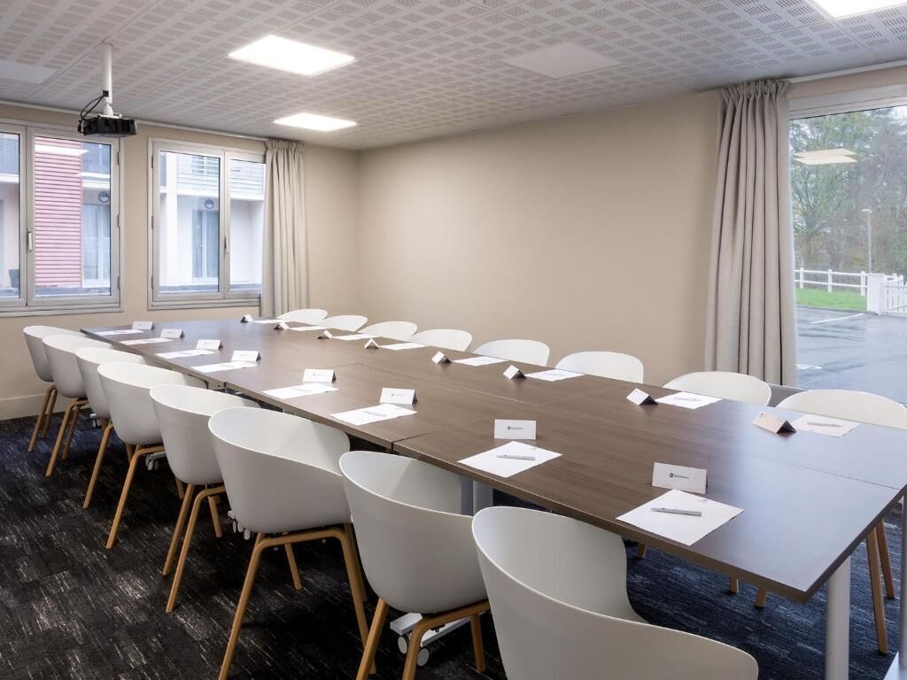 A conference room with a long table, white chairs, name cards, and a projector.