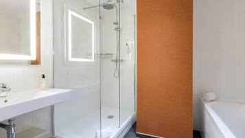 Een moderne badkamer met een douchecabine van glas, een witte wastafel en een wand van hout.
