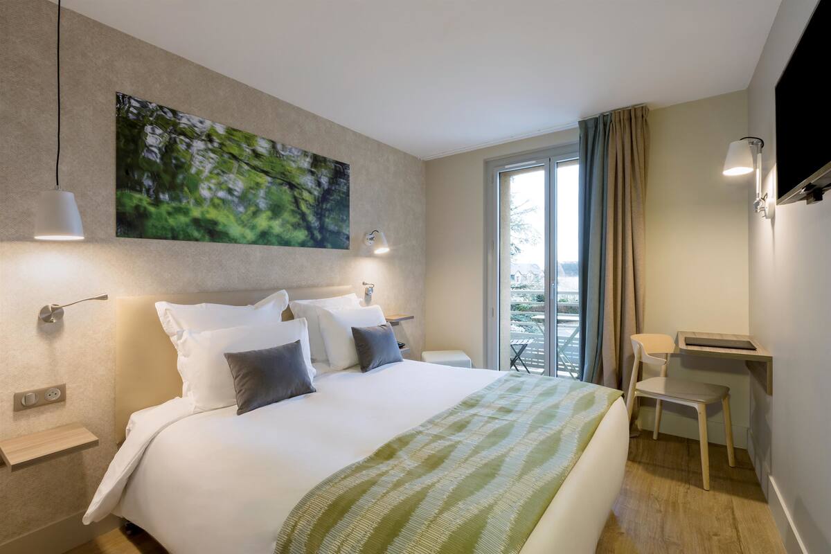 Une chambre d’hôtel moderne dotée d’un grand lit, d’un bureau et offrant une vue sur l’extérieur.