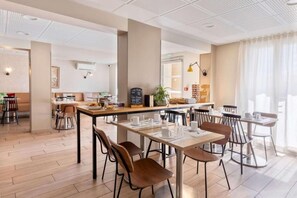 Een modern café met houten vloeren, tafels met stoelen en een krijtbordmenu.