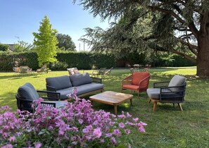 Een terras met tuinmeubilair, waaronder een bank, stoelen en een tafel.