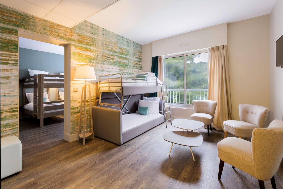 Une pièce comprenant un lit superposé, un canapé, une petite table et deux chaises.