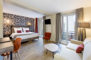 Une chambre d’hôtel équipée d’un lit, d’un bureau, d’une chaise, d’un canapé et d’une télévision.