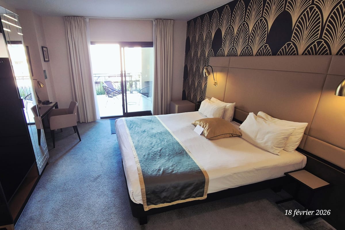 Habitación de hotel con una cama grande, un escritorio, una silla y vistas al exterior por la ventana.