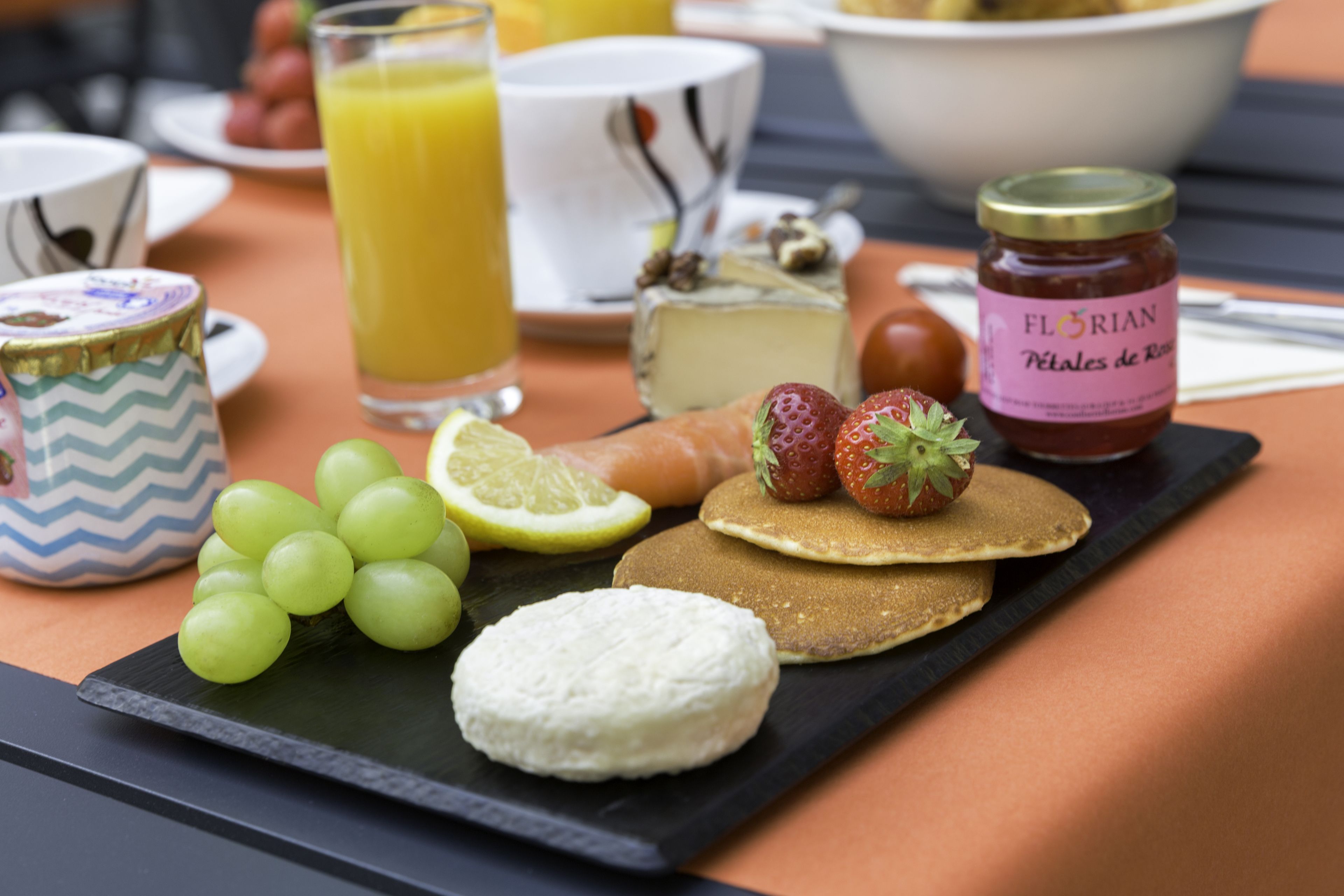 A breakfast setting with a variety of foods including pancakes, strawberries, and a bottle of jam.