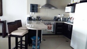 Una cocina compacta con comedor, estufa, microondas y refrigerador.