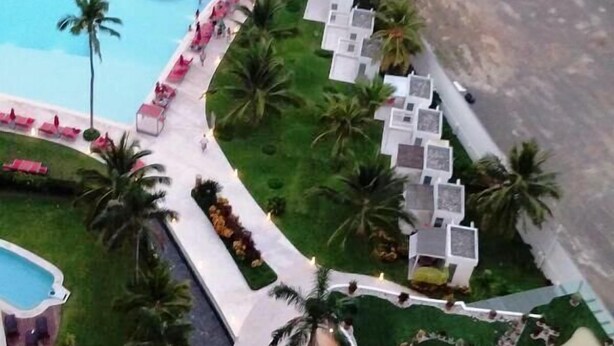 Un resort con piscina, zonas de descanso y vista al mar.
