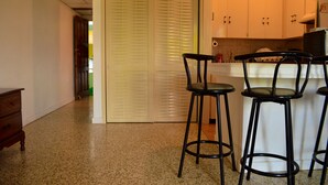 A kitchen with a countertop and three black bar stools. - Crystal Beach Studio (Montego Bay)