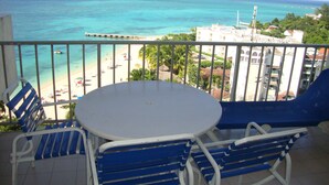 Un balcone con tavolo e sedie affacciato su una spiaggia e l'oceano.