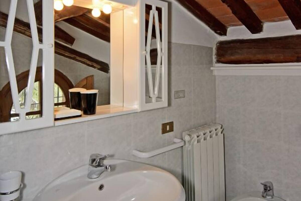 Une salle de bain avec un grand lavabo blanc, un bidet et un miroir doté de cadres géométriques.
