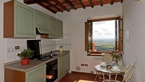 A kitchen with green cabinets, a window with a view, and a dining area with a table and chairs. - I Sette Borghi (Massa e Cozzile)
