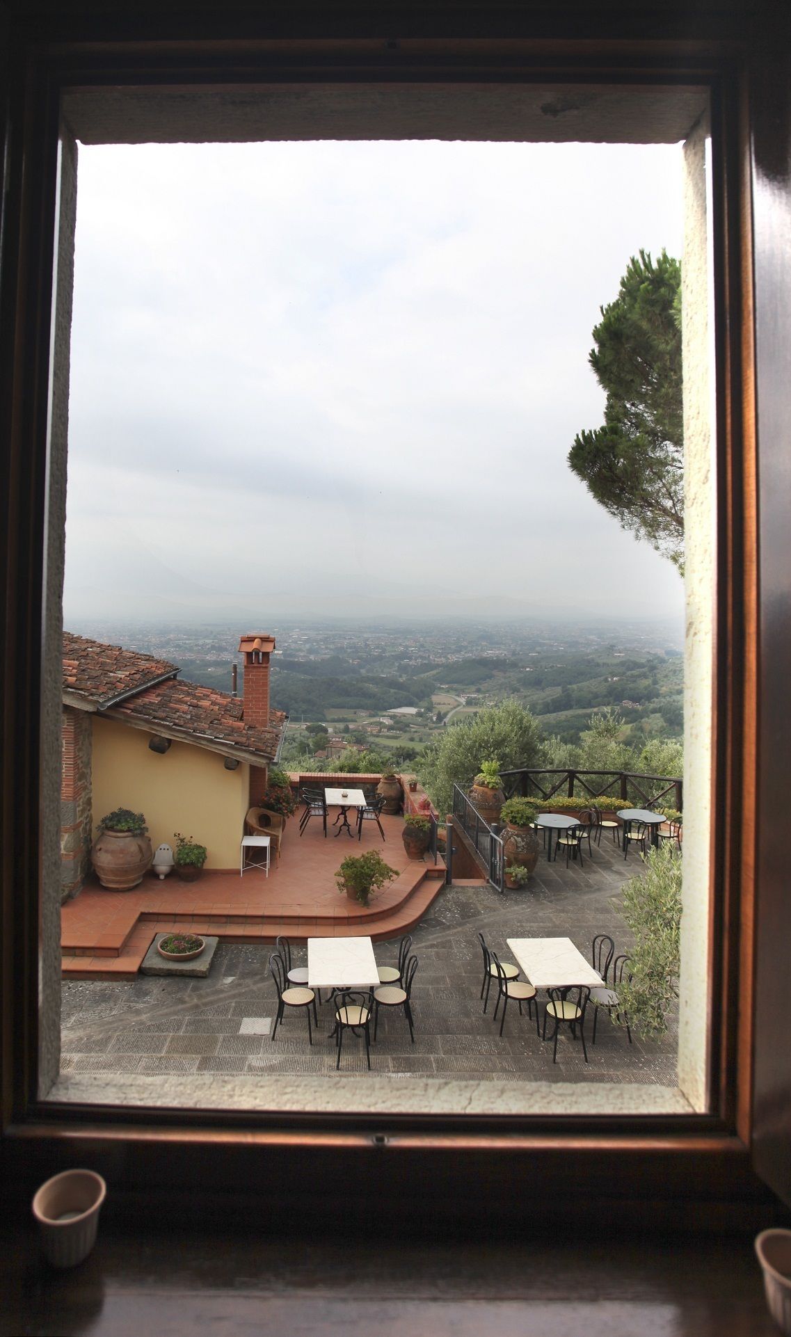 A view from a window overlooking a patio area with outdoor seating and a scenic landscape.