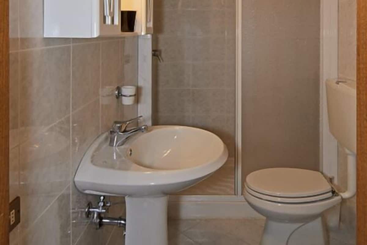 Une salle de bain équipée d’un lavabo sur colonne, de toilettes et d’un espace douche.