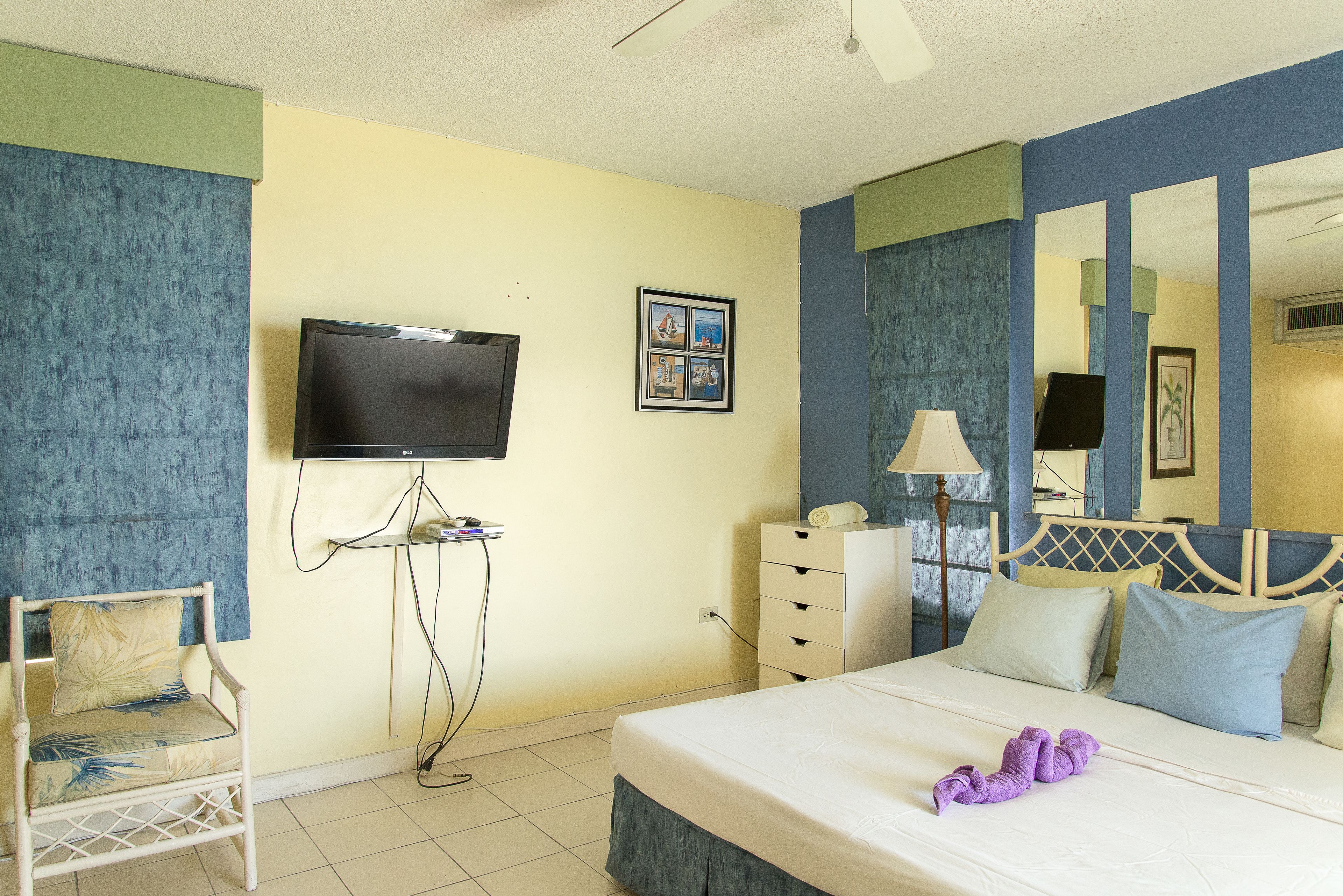 A hotel room with a bed, a chair, a television, a dresser, and a mirror.