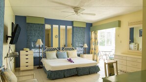 A bedroom with a bed, bedside tables, a chair, a desk, and a ceiling fan. - Hipstrip Beach Studio (Montego Bay)
