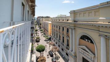 A street view with buildings, trees, and people walking.