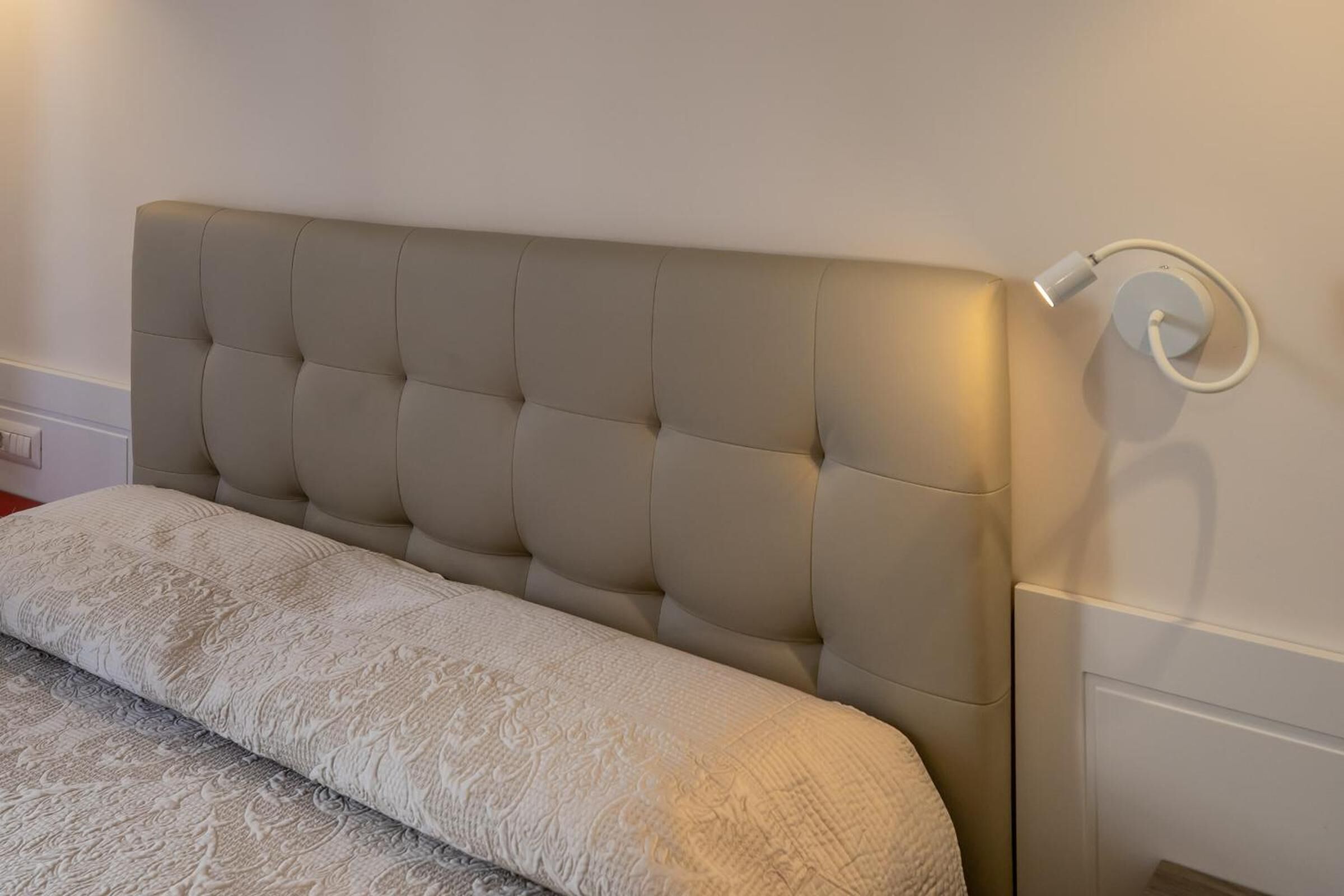 A bed with a tufted headboard and a bedside table with a lamp.