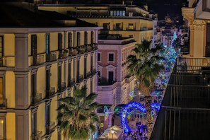 A nighttime view of a city street lined with buildings, decorated with festive lights and palm trees. - Residenza Eleonora (Salerno)