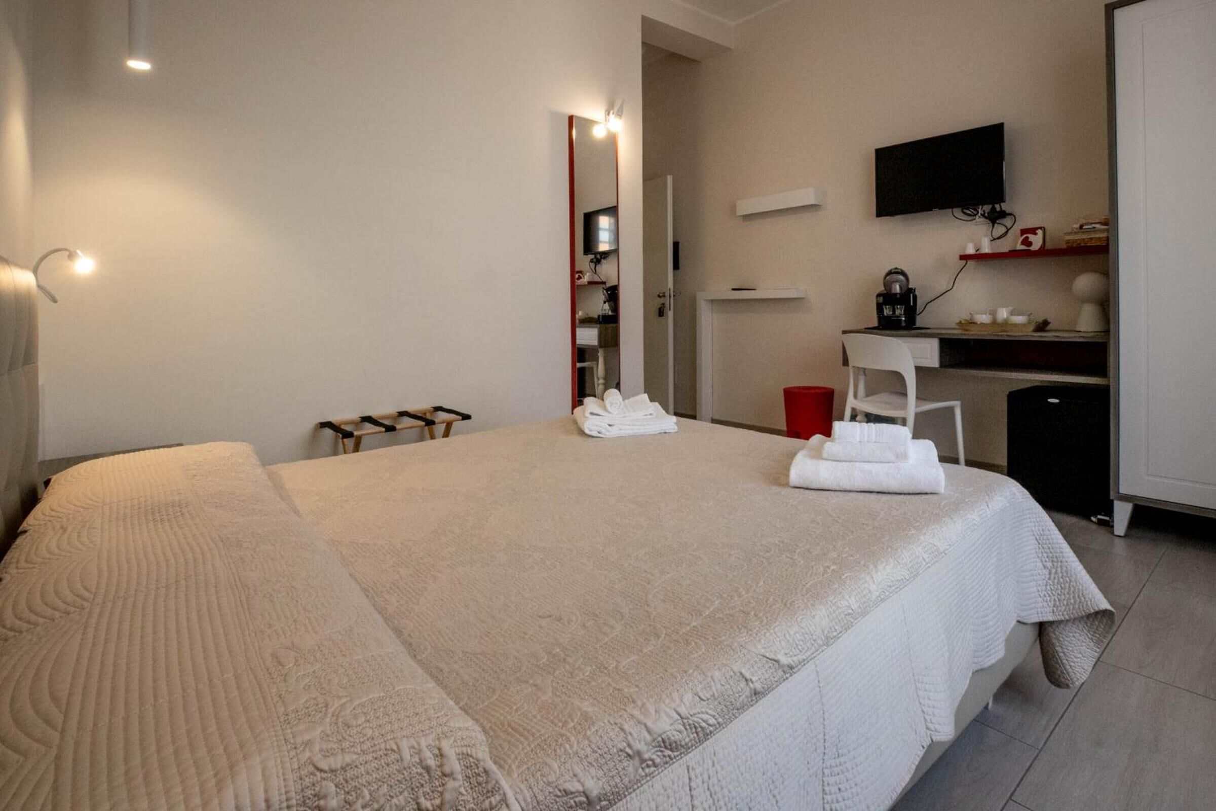 Ein ordentlich eingerichtetes Hotelzimmer mit einem großen Bett, einem Schreibtisch mit Computer, einem Fernseher und einer kleinen Küchenzeile.