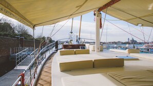 A covered deck with seating areas and a view of the marina. - Veliero Venezia (Venice)