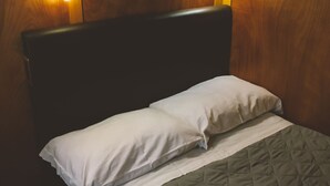 A bed with a quilted mattress and two pillows, set against a wooden headboard and wall. - Veliero Venezia (Venice)