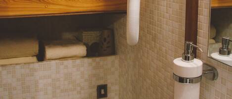 A bathroom with a wooden vanity, a white sink, a towel rack, and a hairdryer mounted on the wall.
