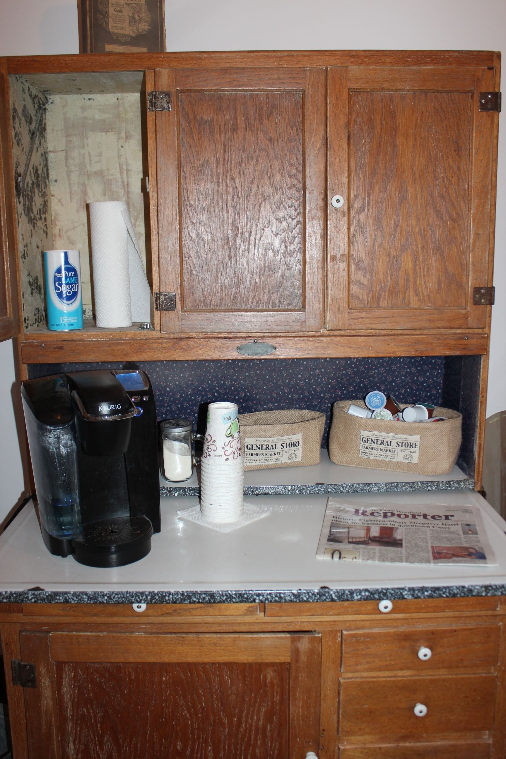 Uma bancada de cozinha com uma cafeteira, papel toalha e duas cestas com a inscrição 'General Store'.