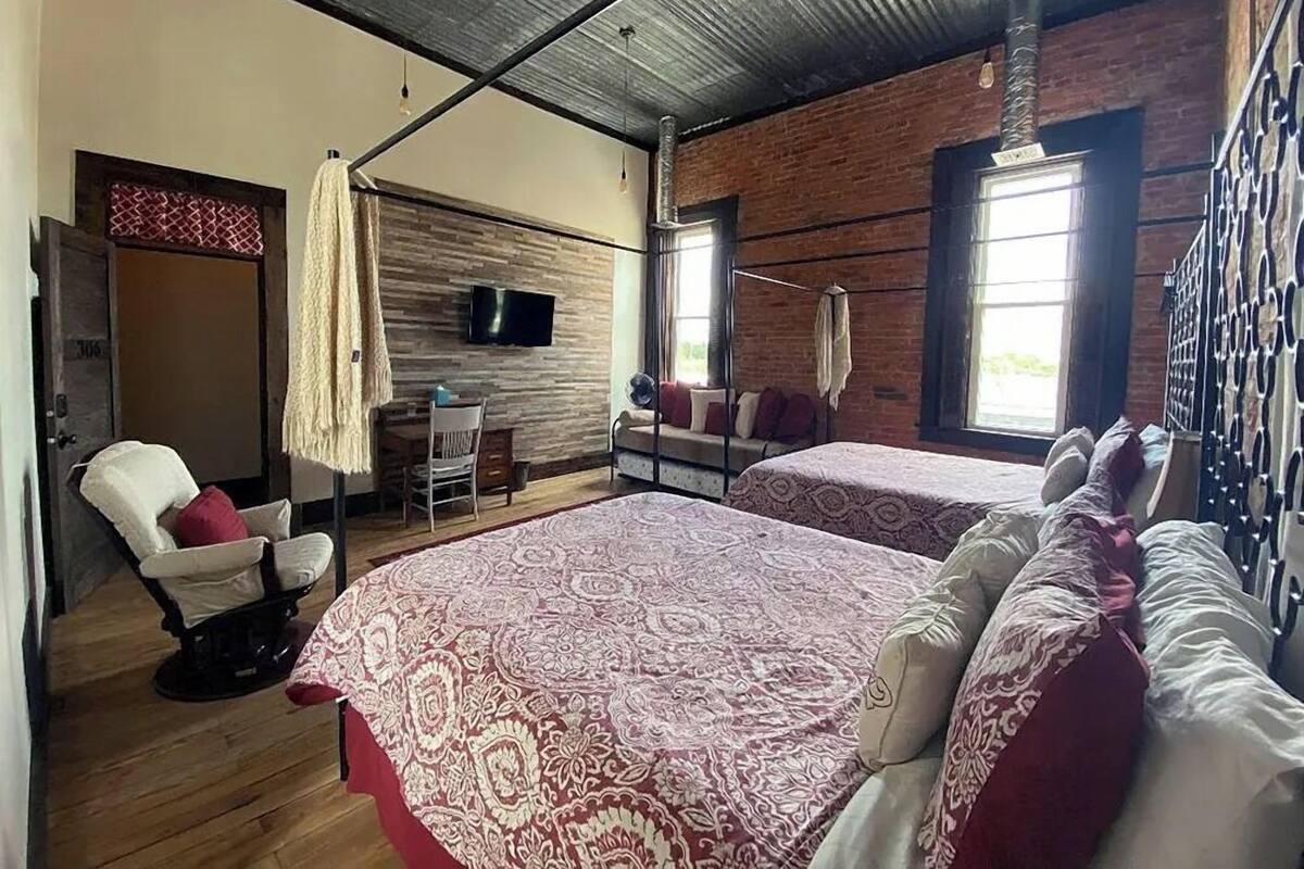 Una habitación con dos camas, televisión, escritorio y una silla.
