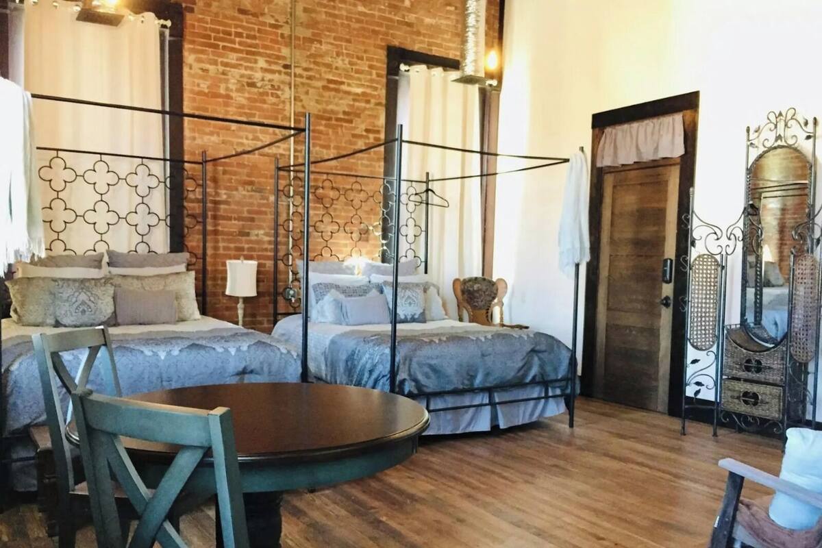 Una habitación con cama con dosel, una mesa de comedor de madera y una silla.
