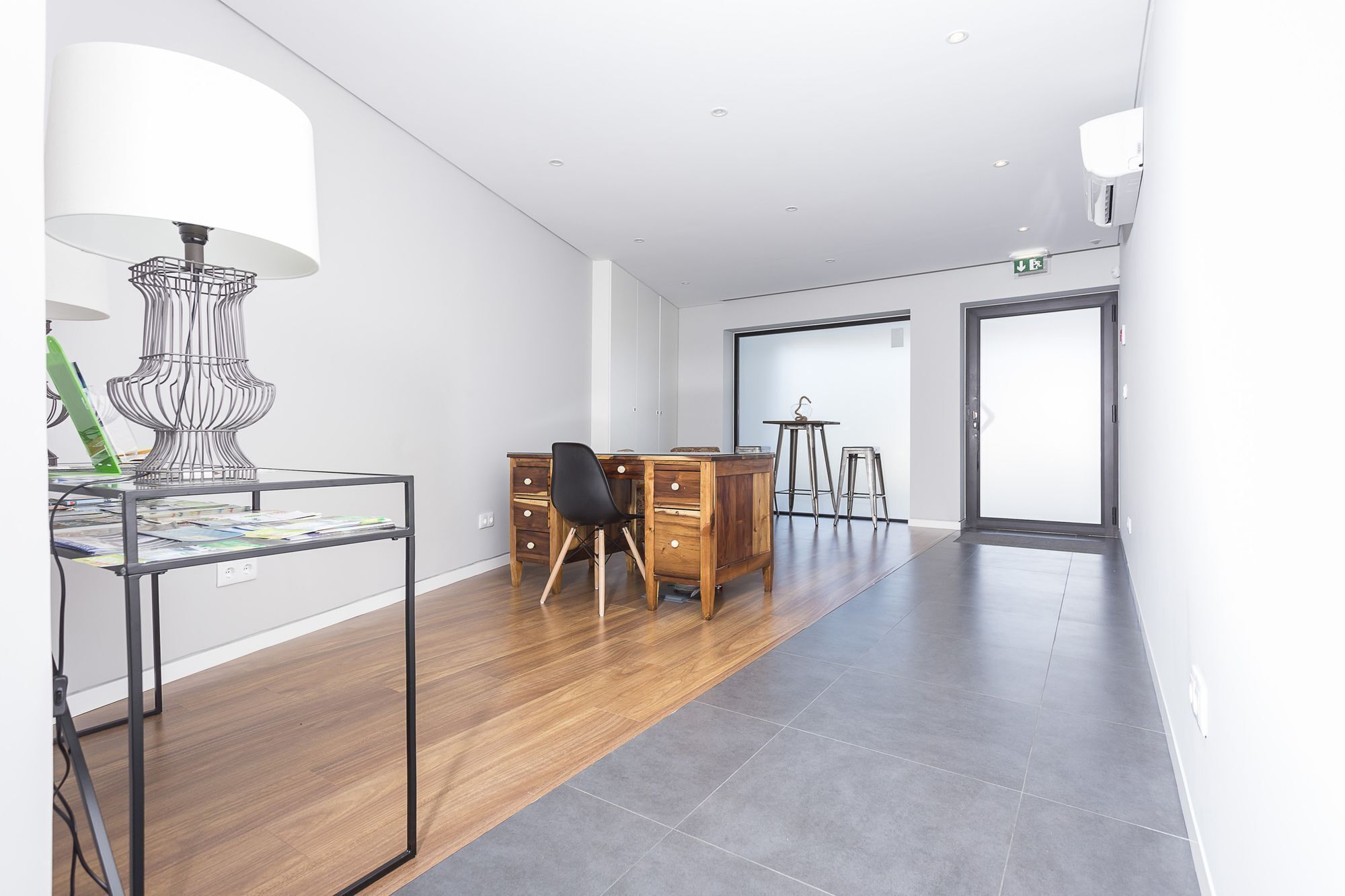 A modern office space with a desk, chair, and lamp.