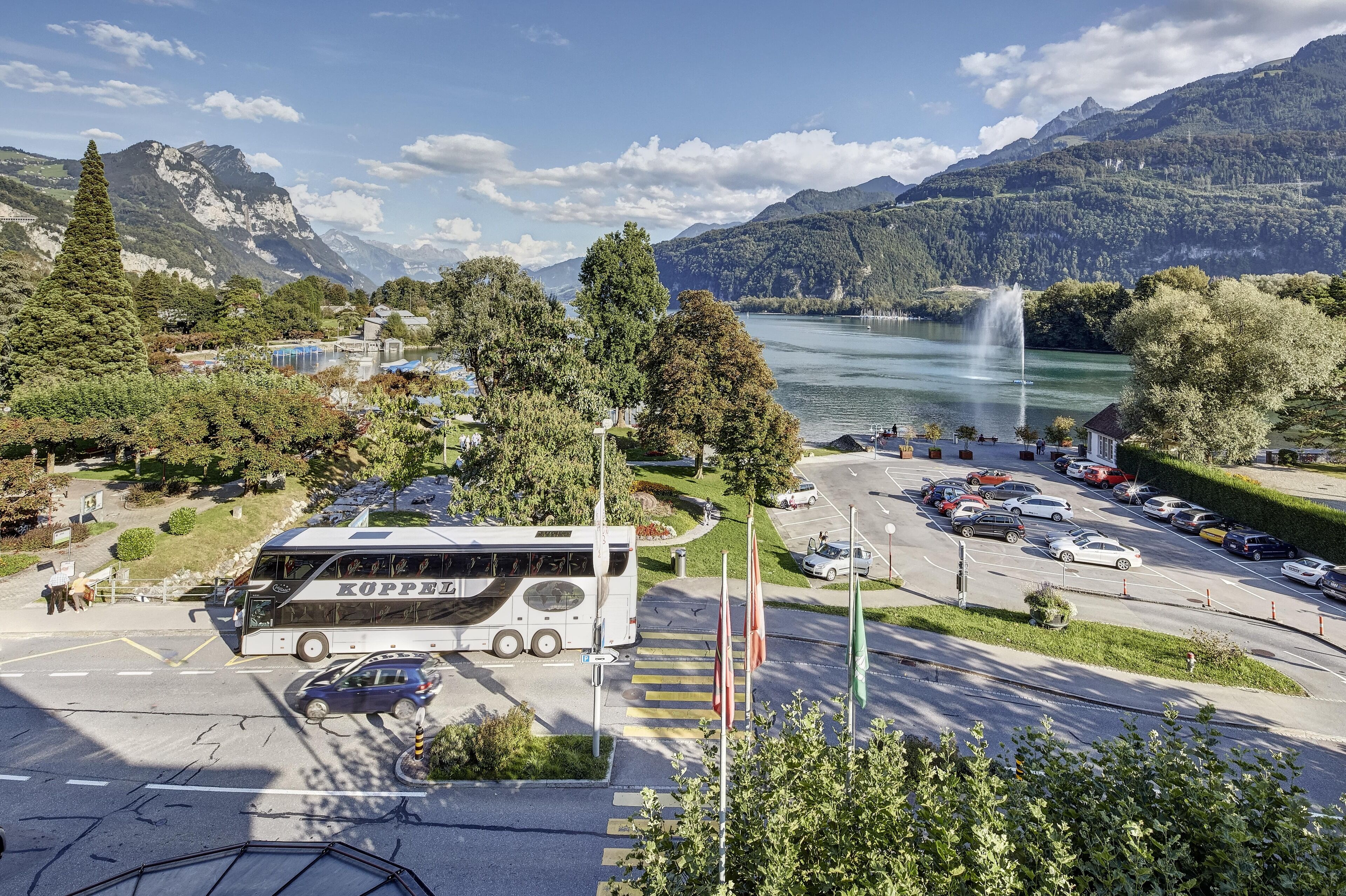 Ein Bus an einer Bushaltestelle vor einer Berglandschaft und einem See.