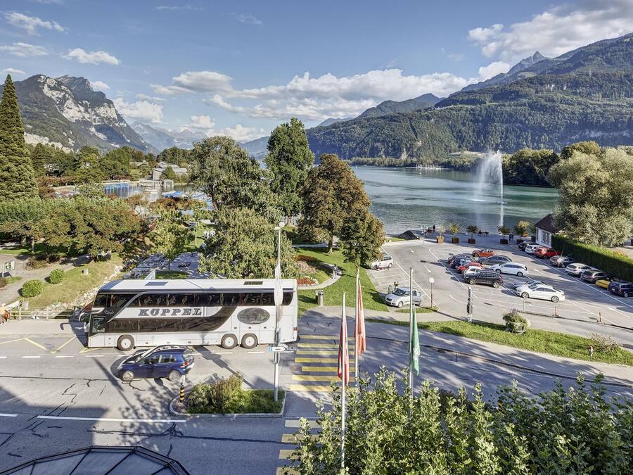 Ein Bus an einer Bushaltestelle vor einer Berglandschaft und einem See.