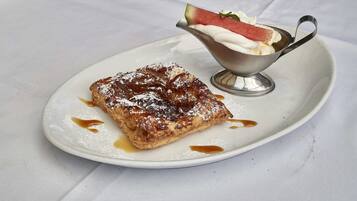 Une assiette à dessert avec une pâtisserie et un petit bol de crème fouettée et de fruits.