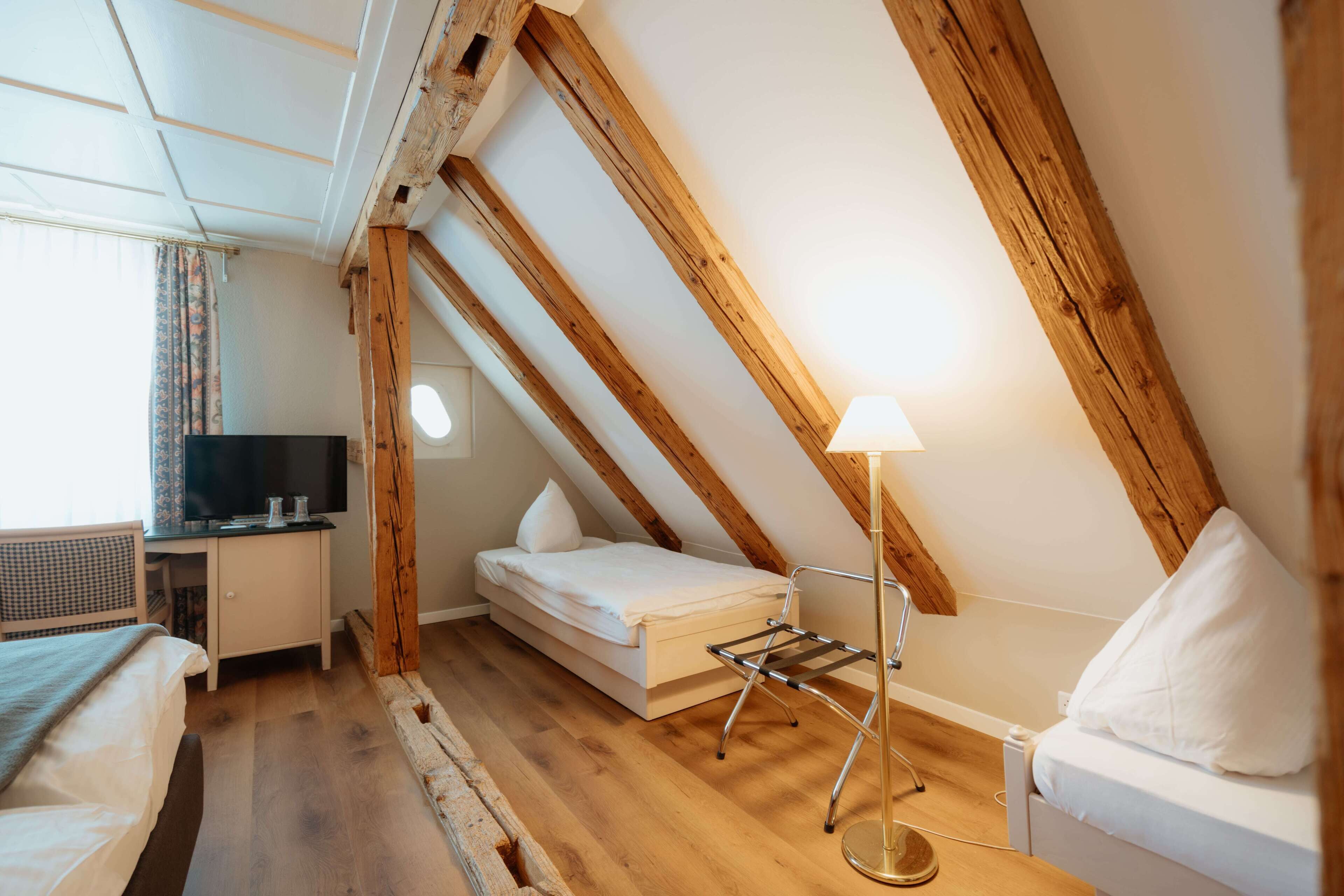A small, cozy room with a loft bed, a desk with a computer, and a lamp.
