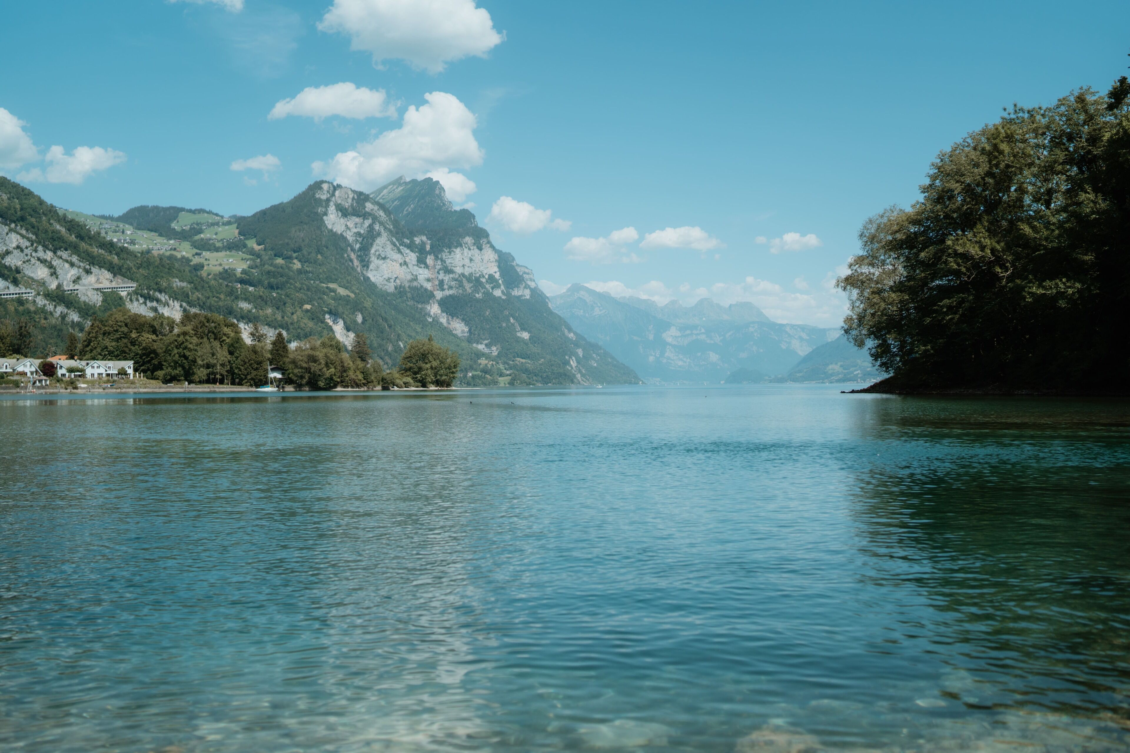 A calm lake with mountains in the background and a clear sky.