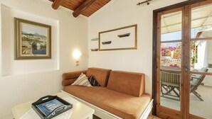 A cozy living room with a brown sofa, a small table with a tray, and a framed picture on the wall. - Olympia Village (Samos)